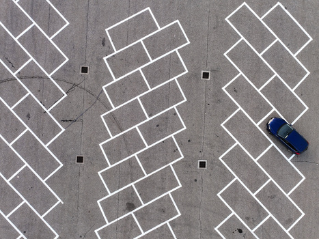 Aerial view of a parking lot with white geometric lines and a single blue car parked on the asphalt Borgo d Ale Piedmont Italy.