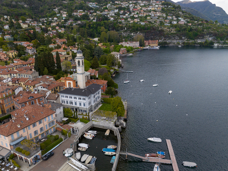 Aerial view of the waterfront featuring the Church of San Vincenzo bell tower colorful lakeside buildings and the historic Villa d Este complex on Lake Como Cernobbio Lombardia Italy. Aerial view of the waterfront featuring the Church of San Vincenzo bell tower colorful lakeside buildings and the historic Villa d Este complex on Lake Como Cernobbio Lombardia Italy.
