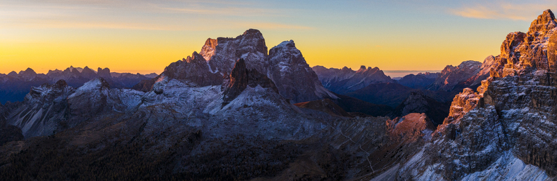 Aerial view of jagged peaks kissed by the golden dawn snow dusting their slopes under a vivid sky SP2 Veneto Italy.