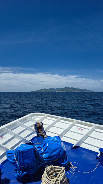 View of the bow of a boat with blue covers and coiled rope looking out towards the distant island of Ko Tao under a clear blue sky in Ko Tao Surat Thani Thailand.