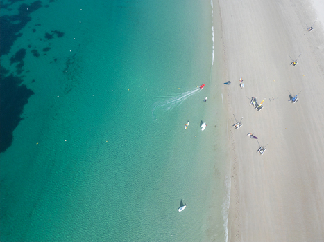 Aerial view of the turquoise waters and white sandy beach with small boats and catamarans on the shore in Trebeurden Brittany France. Aerial view of the turquoise waters and white sandy beach with small boats and catamarans on the shore in Trebeurden Brittany France.