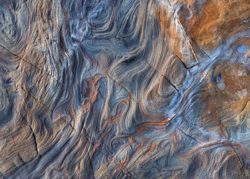View of intricate swirling patterns and eroded textures on the coastal sandstone rocks of Calafuria Toscana Italy.