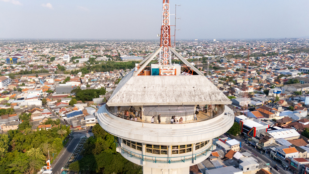 Aerial view of the observation tower with visitors on the viewing deck surrounded by the dense urban landscape of the city in Semarang Central Java Indonesia. Aerial view of the observation tower with visitors on the viewing deck surrounded by the dense urban landscape of the city in Semarang Central Java Indonesia.