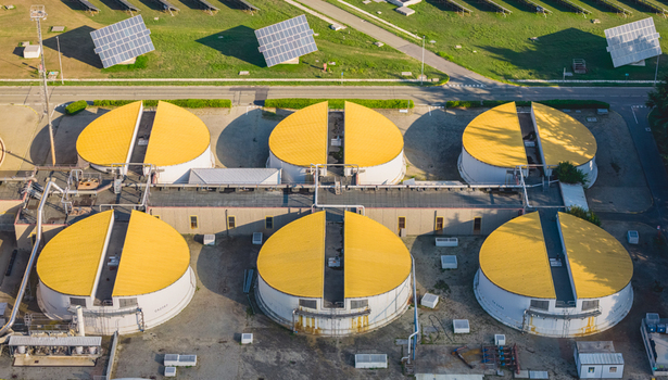 Aerial view of circular sludge treatment tanks with yellow covers and solar panels at a wastewater treatment and biogas facility in Italy. Aerial view of circular sludge treatment tanks with yellow covers and solar panels at a wastewater treatment and biogas facility in Italy.