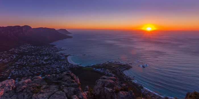 View of the coastline and mountains at sunset with the sun setting over the Atlantic Ocean in South Africa.