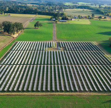Aerial view of a large solar farm with rows of photovoltaic panels set in green agricultural fields in Woodburn Oregon United States. Aerial view of a large solar farm with rows of photovoltaic panels set in green agricultural fields in Woodburn Oregon United States.