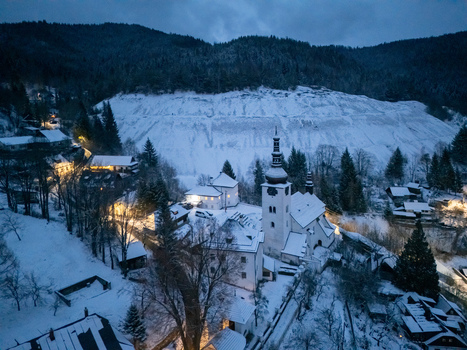 Aerial view of historic village of Spania Dolina with its church tower and snow covered rooftops nestled in the forested hills at dusk in Spania Dolina Banska Bystrica Region Slovakia. Aerial view of historic village of Spania Dolina with its church tower and snow covered rooftops nestled in the forested hills at dusk in Spania Dolina Banska Bystrica Region Slovakia.