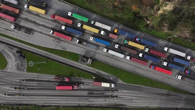 Aerial view of trucks lined up on road with shipping containers Portugal.