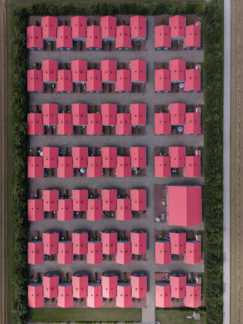 Aerial view of prefabricated housing for migrant and seasonal workers with rows of identical houses with red roofs surrounded by green hedges Swifterbant Flevoland Netherlands. Aerial view of prefabricated housing for migrant and seasonal workers with rows of identical houses with red roofs surrounded by green hedges Swifterbant Flevoland Netherlands.