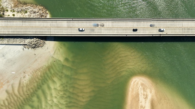 Aerial view of Matanzas Inlet bridge spanning turquoise waters with sandbars and cars driving across the concrete structure in St. Johns County Florida United States. Aerial view of Matanzas Inlet bridge spanning turquoise waters with sandbars and cars driving across the concrete structure in St. Johns County Florida United States.