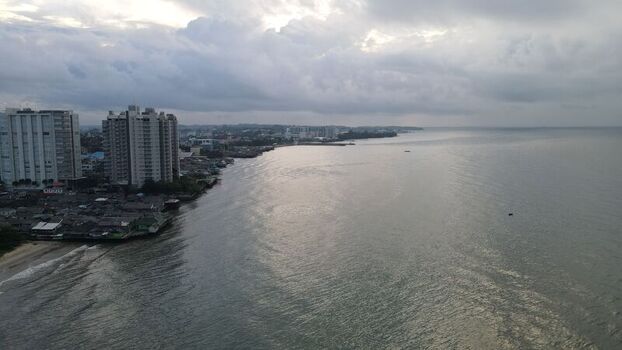 Aerial view of the coastal city of Balikpapan with high rise buildings along the shoreline and calm sea under a cloudy sky in Balikpapan East Kalimantan Indonesia. Aerial view of the coastal city of Balikpapan with high rise buildings along the shoreline and calm sea under a cloudy sky in Balikpapan East Kalimantan Indonesia.