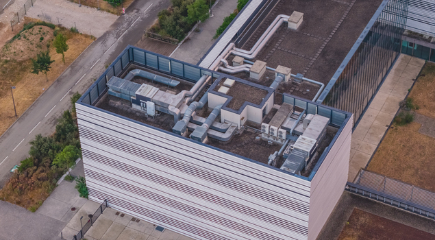 Aerial view of a modern commercial building featuring rooftop HVAC equipment ventilation ducts and mechanical infrastructure in Alixan Auvergne Rhone Alpes France.