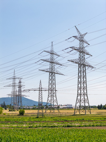 Aerial view of the Amprion Umspannwerk substation with high voltage electricity pylons stretching across rural fields under a clear blue sky in Pfungstadt Hessen Germany.