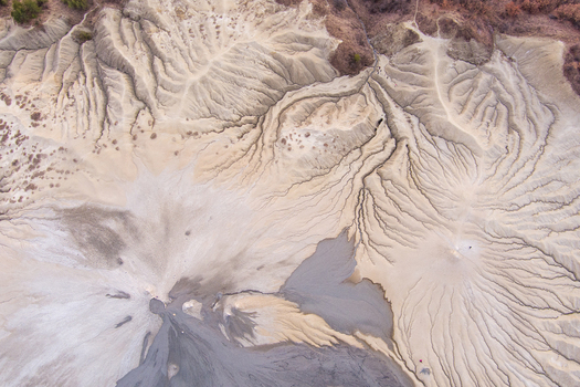 Aerial view of the Mud Volcanoes of Paclele Mari showing intricate patterns of dried mud and grey volcanic sediment in Paclele Buzau County Romania.