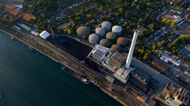 Aerial view of the Grosskraftwerk Mannheim power plant with its large storage tanks tall chimney and industrial facilities situated along the river in Mannheim Baden Wurttemberg Germany.