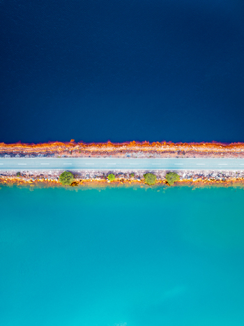 Aerial view of a road separating two contrasting bodies of water with vibrant orange mineralized banks and small green trees in Andalusia Spain. Aerial view of a road separating two contrasting bodies of water with vibrant orange mineralized banks and small green trees in Andalusia Spain.
