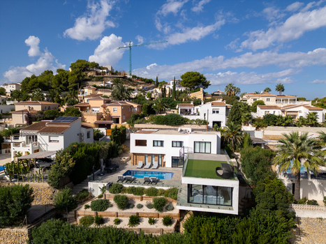 Aerial view of a modern villa with a swimming pool and landscaped gardens in a residential area of Moraira Valencian Community Spain.