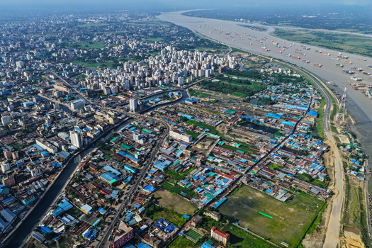 Aerial view of Karnaphuli River flowing past the dense urban landscape of Chattogram Chittagong Division Bangladesh.