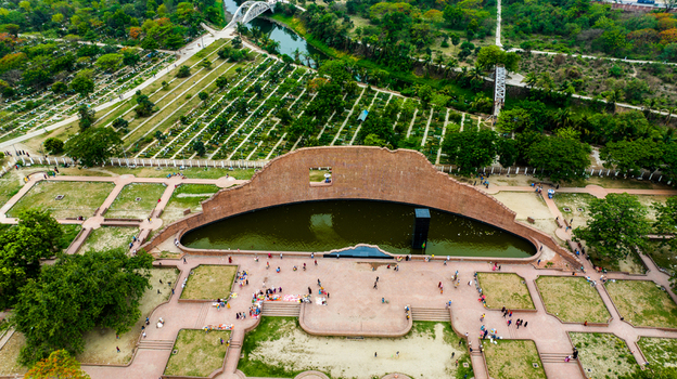 Aerial view of Rayer Bazaar Memorial with its iconic curved brick wall reflecting pool and black monolith surrounded by lush parkland in Dhaka Dhaka Division Bangladesh.