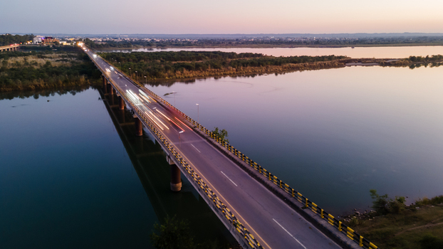 Aerial view of the Jhelum River bridge with car light trails at dusk surrounded by lush greenery and the city skyline in Jhelum Punjab Pakistan. Aerial view of the Jhelum River bridge with car light trails at dusk surrounded by lush greenery and the city skyline in Jhelum Punjab Pakistan.