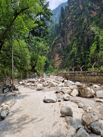 View of a road blocked by large rocks and debris following a landslide in the mountainous terrain of Malana Himachal Pradesh India.