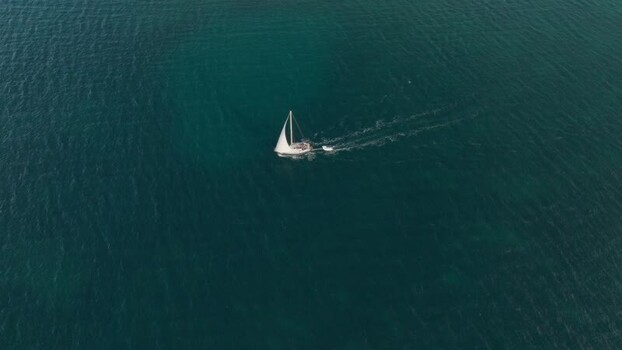 Aerial view of a white sailboat cruising on the blue sea Italy. Aerial view of a white sailboat cruising on the blue sea Italy.