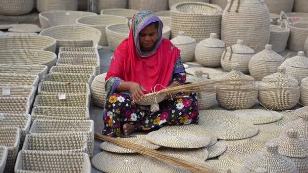 View of a woman weaving traditional baskets in Bogura Bangladesh. View of a woman weaving traditional baskets in Bogura Bangladesh.