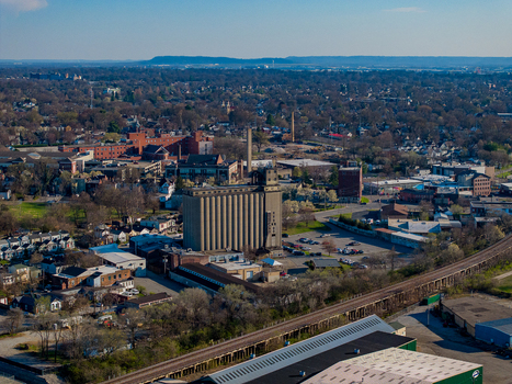 Aerial view of a large industrial grain elevator surrounded by urban neighborhoods and a railway line under a clear blue sky in Louisville Kentucky United States. Aerial view of a large industrial grain elevator surrounded by urban neighborhoods and a railway line under a clear blue sky in Louisville Kentucky United States.