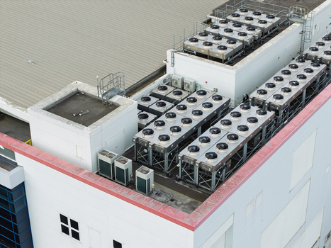Aerial view of a data center rooftop featuring rows of industrial HVAC cooling units and ventilation systems in the United Kingdom.