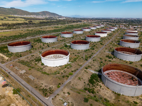 Aerial view of large industrial oil storage tanks in the Milnerton area surrounded by dry vegetation and paths under a clear blue sky in Cape Town Western Cape South Africa. Aerial view of large industrial oil storage tanks in the Milnerton area surrounded by dry vegetation and paths under a clear blue sky in Cape Town Western Cape South Africa.