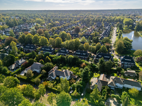 View of residential houses surrounded by lush green trees and gardens in the historic town of Naarden North Holland Netherlands. View of residential houses surrounded by lush green trees and gardens in the historic town of Naarden North Holland Netherlands.