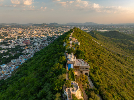Aerial view of the Karni Mata Temple perched on a lush green hill overlooking the sprawling city of Udaipur Rajasthan India.