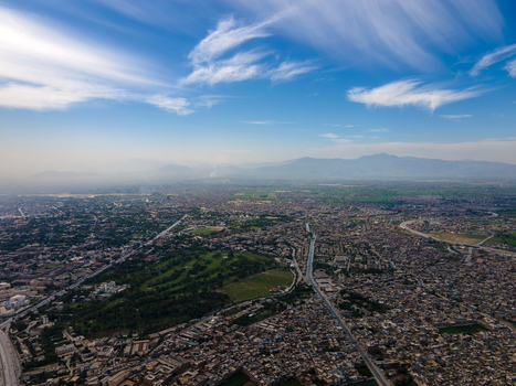 Aerial view of the historic Bala Hisar Fort surrounded by the dense urban landscape of Peshawar with distant mountains under a clear blue sky in Peshawar Khyber Pakhtunkhwa Pakistan.