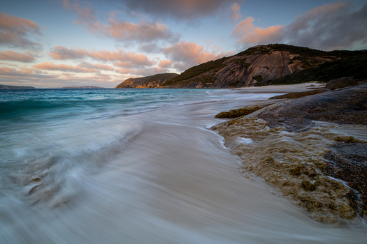View of Misery Beach with waves washing over the white sand rocky coastline and soft sunset light in Torndirrup Western Australia Australia. View of Misery Beach with waves washing over the white sand rocky coastline and soft sunset light in Torndirrup Western Australia Australia.
