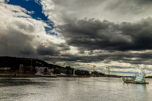 View of a cloudy skyline over the calm waters with construction cranes dotting the landscape creating a contrast between nature and industry West Old Town New Mexico Sweden. View of a cloudy skyline over the calm waters with construction cranes dotting the landscape creating a contrast between nature and industry West Old Town New Mexico Sweden.