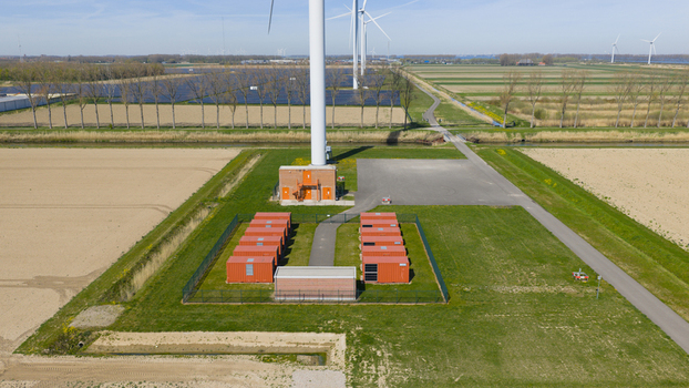 Aerial view of a wind turbine base and energy storage facility with red containers and solar panels in Middelharnis South Holland Netherlands. Aerial view of a wind turbine base and energy storage facility with red containers and solar panels in Middelharnis South Holland Netherlands.