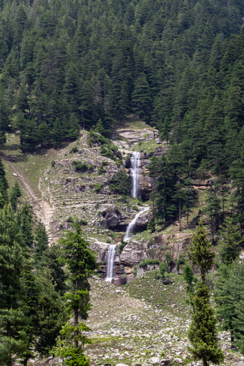 View of a cascading waterfall flowing down a rocky mountainside surrounded by a dense coniferous forest in Kumrat Valley Khyber Pakhtunkhwa Pakistan. View of a cascading waterfall flowing down a rocky mountainside surrounded by a dense coniferous forest in Kumrat Valley Khyber Pakhtunkhwa Pakistan.