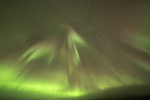 View of the vibrant green and reddish Aurora Borealis dancing across a starry night sky over the landscape of Olafsvik Snaefellsbaer Iceland.