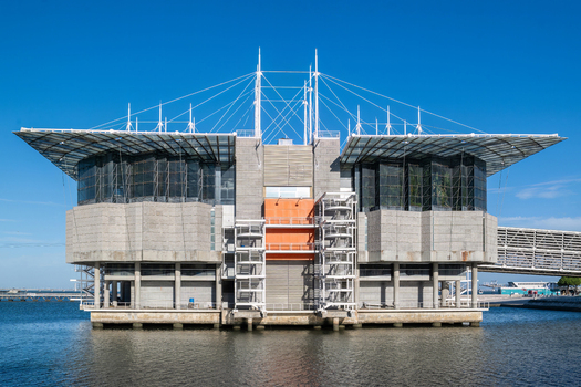 Lisboa Portugal 17 September 2026 View of the Oceanario de Lisboa a modern aquarium building with glass walls and a distinctive orange central section situated on the water under a clear blue sky. Lisboa Portugal 17 September 2026 View of the Oceanario de Lisboa a modern aquarium building with glass walls and a distinctive orange central section situated on the water under a clear blue sky.