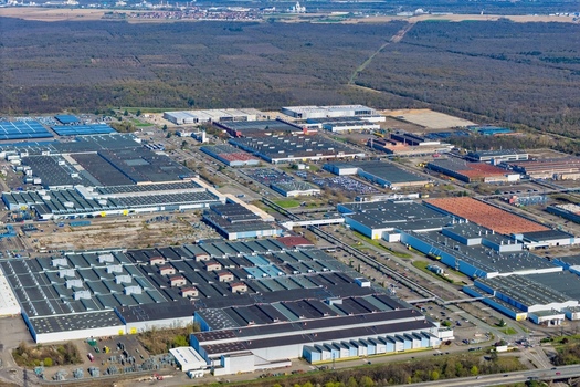 Aerial view of sprawling industrial complex meeting the edge of a dense forest under a vast sky a symphony of human endeavor and natural tranquility Sausheim Grand Est France.