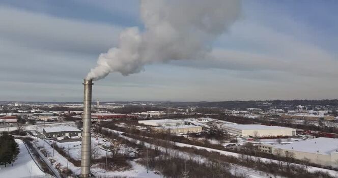 Aerial view of industrial smokestack emitting smoke in winter United States. Aerial view of industrial smokestack emitting smoke in winter United States.