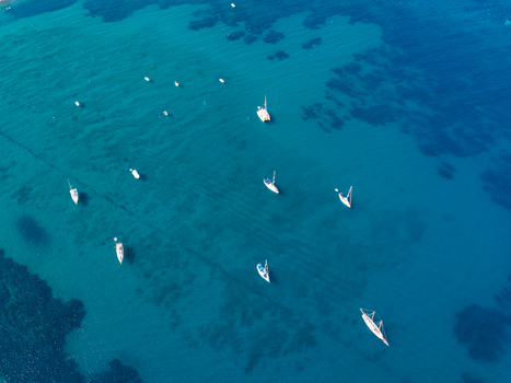 Aerial view of sailboats anchored in the clear turquoise waters of the Mediterranean Sea off the coast of Lacona Tuscany Italy.