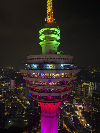 Kuala Lumpur Malaysia 11 March 2026 Aerial view of the Menara Kuala Lumpur tower illuminated with colorful lights against the night city skyline.