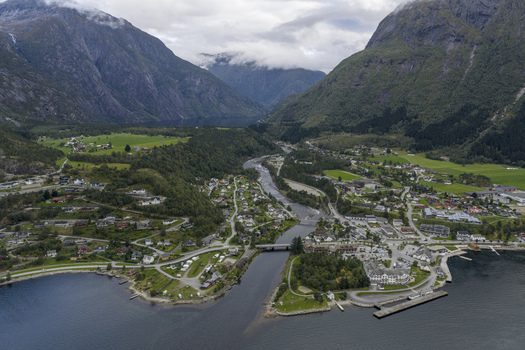 Aerial view of the town of Eidfjord nestled in a green valley between towering mountains with a river winding through the village into the fjord Eidfjord Vestland Norway. Aerial view of the town of Eidfjord nestled in a green valley between towering mountains with a river winding through the village into the fjord Eidfjord Vestland Norway.