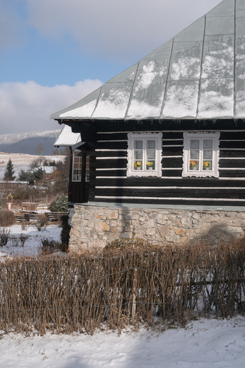View of a charming dark wood and stone house with snow dusted roof and bright window boxes nestled in a winter landscape Donovaly Slovakia. View of a charming dark wood and stone house with snow dusted roof and bright window boxes nestled in a winter landscape Donovaly Slovakia.