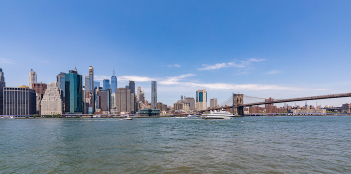View of the Manhattan skyline and the Brooklyn Bridge over the East River under a clear blue sky in New York New York United States. View of the Manhattan skyline and the Brooklyn Bridge over the East River under a clear blue sky in New York New York United States.