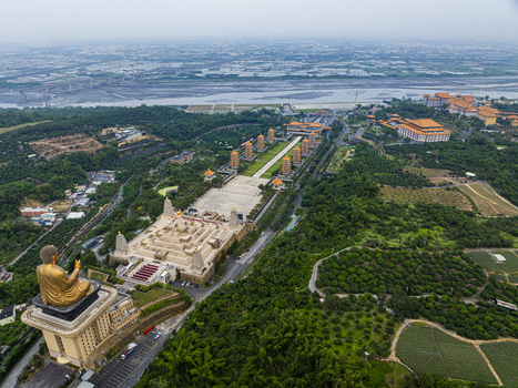 Aerial view of Fo Guang Shan Buddha Museum with its golden Buddha statue pagodas and expansive grounds surrounded by lush greenery and fields in Jiuru Township Pingtung County Taiwan. Aerial view of Fo Guang Shan Buddha Museum with its golden Buddha statue pagodas and expansive grounds surrounded by lush greenery and fields in Jiuru Township Pingtung County Taiwan.