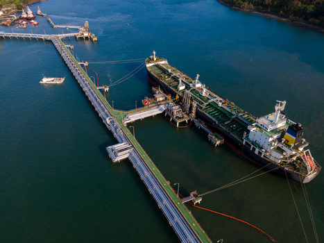 Aerial view of a large oil tanker docked at an industrial pier in a harbor in Cilacap Regency Central Java Indonesia. Aerial view of a large oil tanker docked at an industrial pier in a harbor in Cilacap Regency Central Java Indonesia.