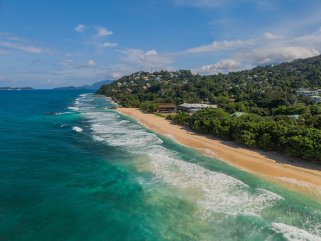 Aerial view of the shoreline where turquoise waters meet the sandy beach framed by lush green hills La Retraite Mahe Island Seychelles. Aerial view of the shoreline where turquoise waters meet the sandy beach framed by lush green hills La Retraite Mahe Island Seychelles.