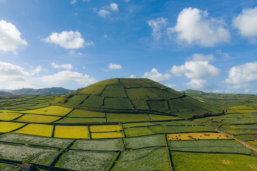 Aerial view of Pico Dona Joana geodesico volcanic cone surrounded by a patchwork of green agricultural fields and stone walls in Feteira Acores Portugal.